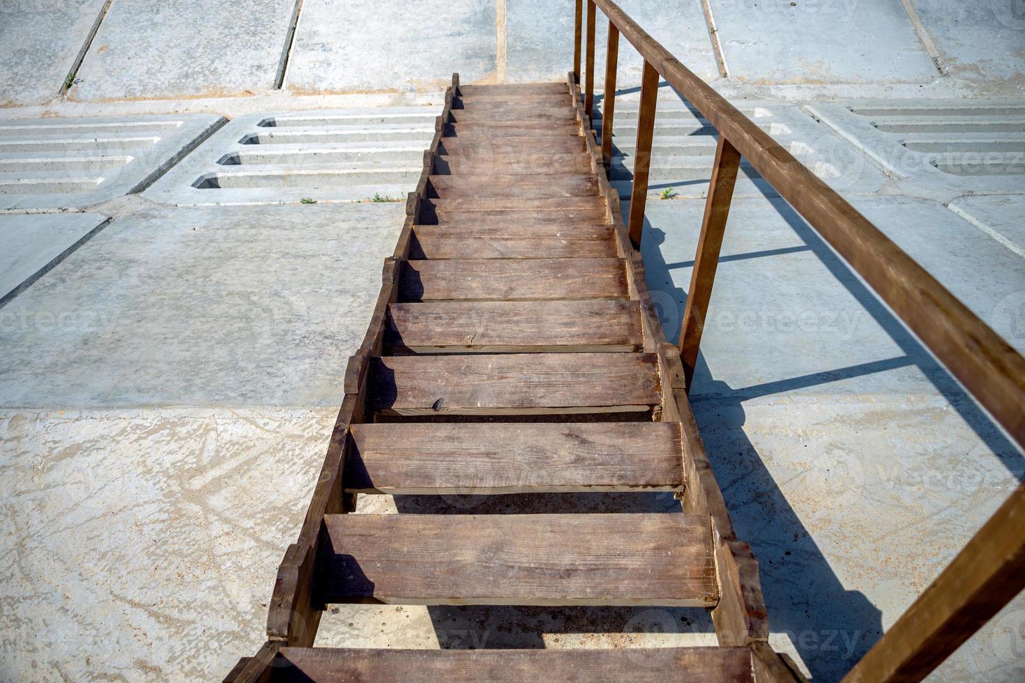 escalones de madera que bajan por una pendiente, escalera de madera con una barandilla foto