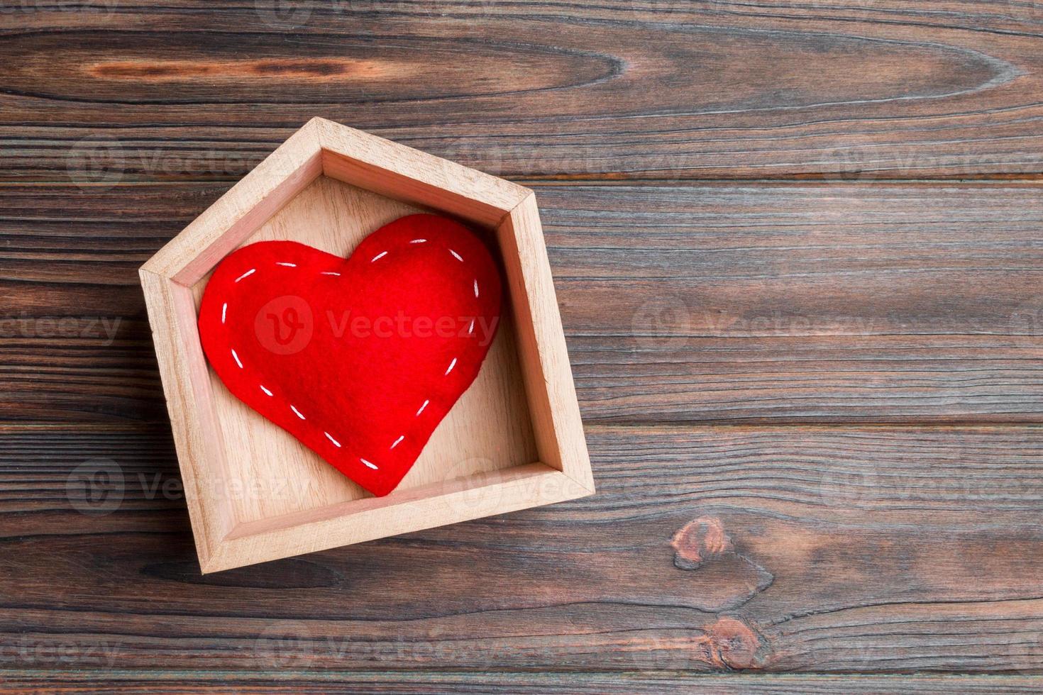 vista superior del corazón textil rojo en una casa sobre fondo de madera. concepto de hogar dulce hogar. día de San Valentín foto