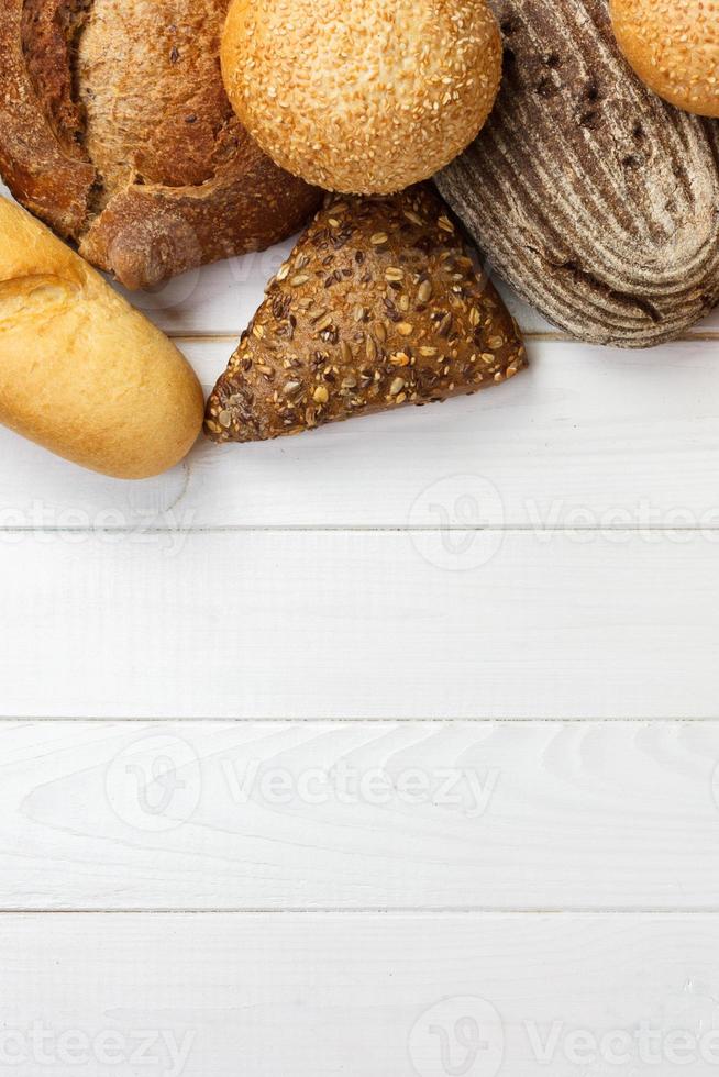 surtido de pan fresco sobre un fondo blanco de madera. vista superior con espacio de copia foto