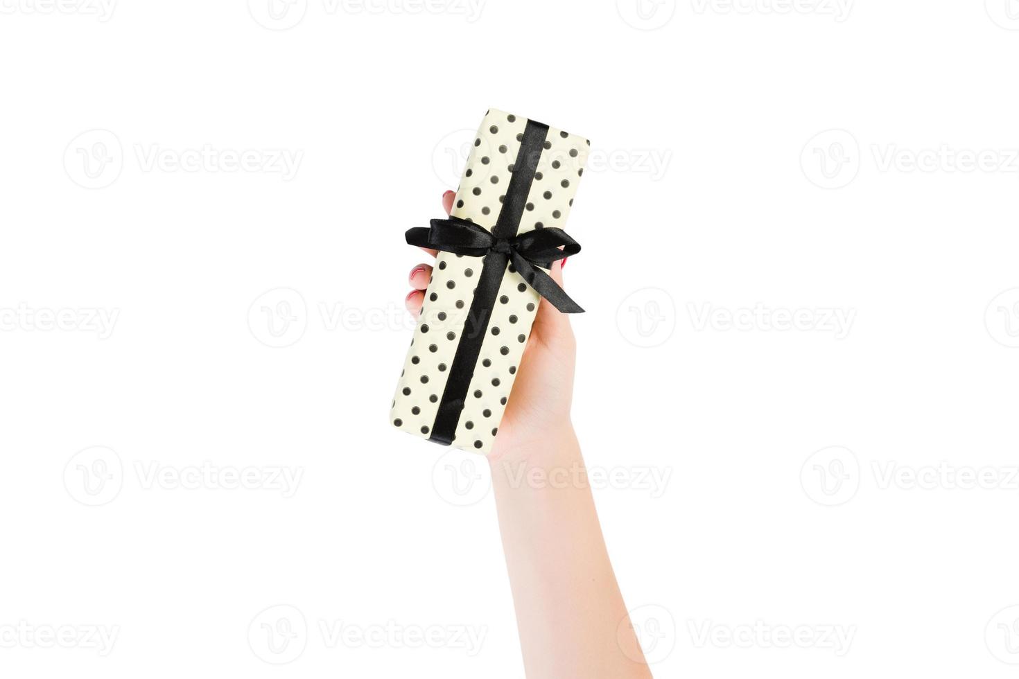 Woman hands give wrapped Christmas or other holiday handmade present in yellow paper with black ribbon. Isolated on white background, top view. thanksgiving Gift box concept photo