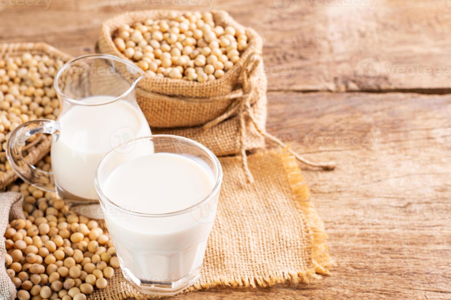 leche de soja en un vaso con soja en una mesa de madera desayuno orgánico, alto en proteínas, productos agrícolas saludables, vegetariano foto