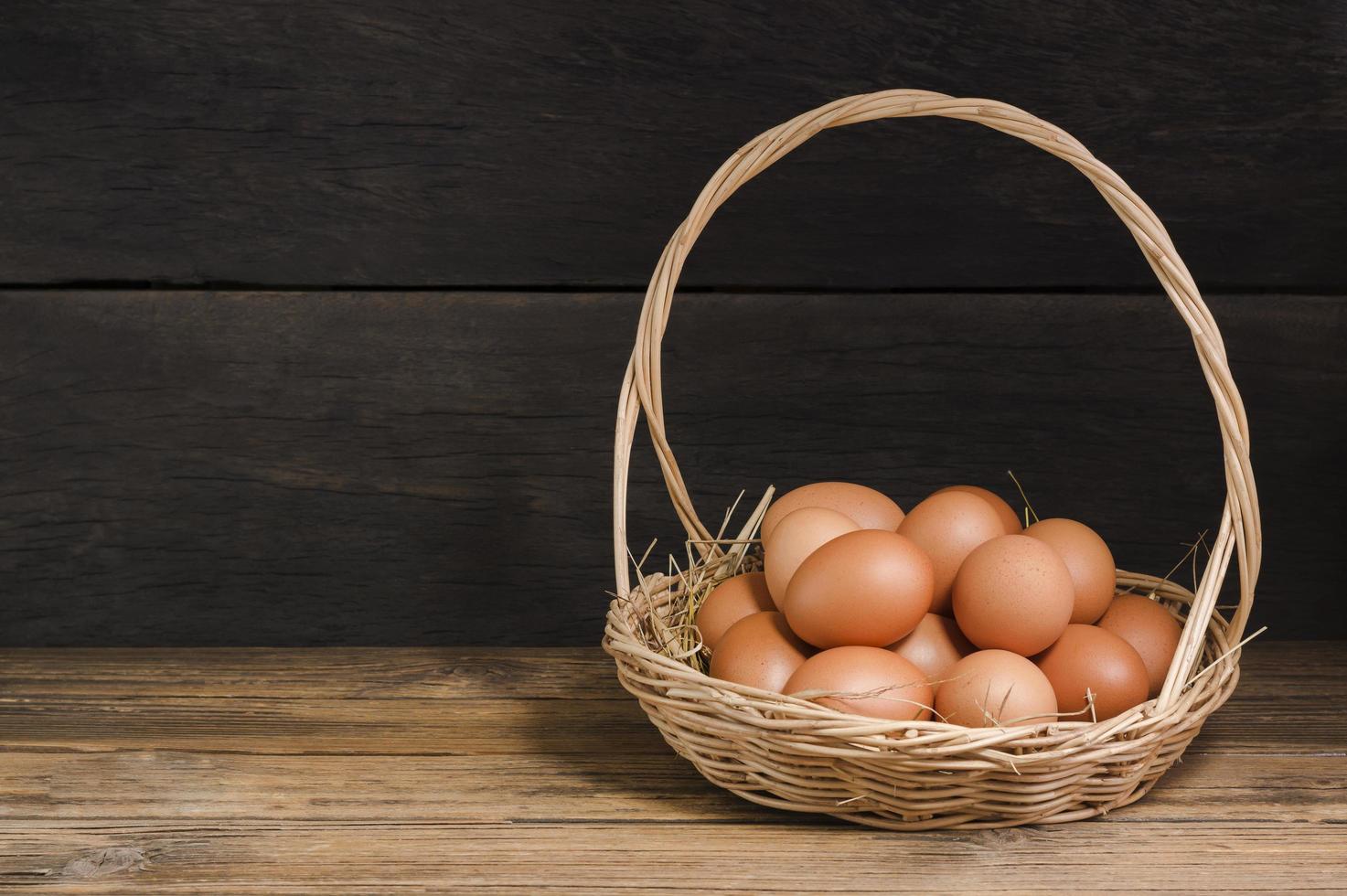 Organic chicken eggs in a basket fresh from the farm, laid on a wooden table, rustic atmosphere. photo