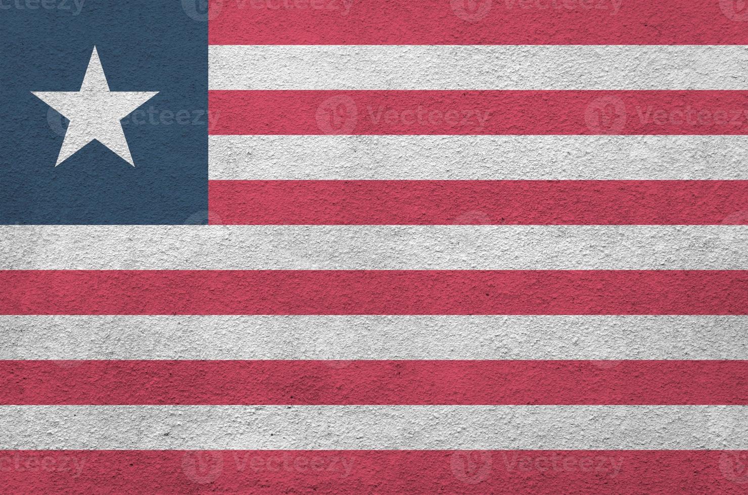 Liberia flag depicted in bright paint colors on old relief plastering wall. Textured banner on rough background photo