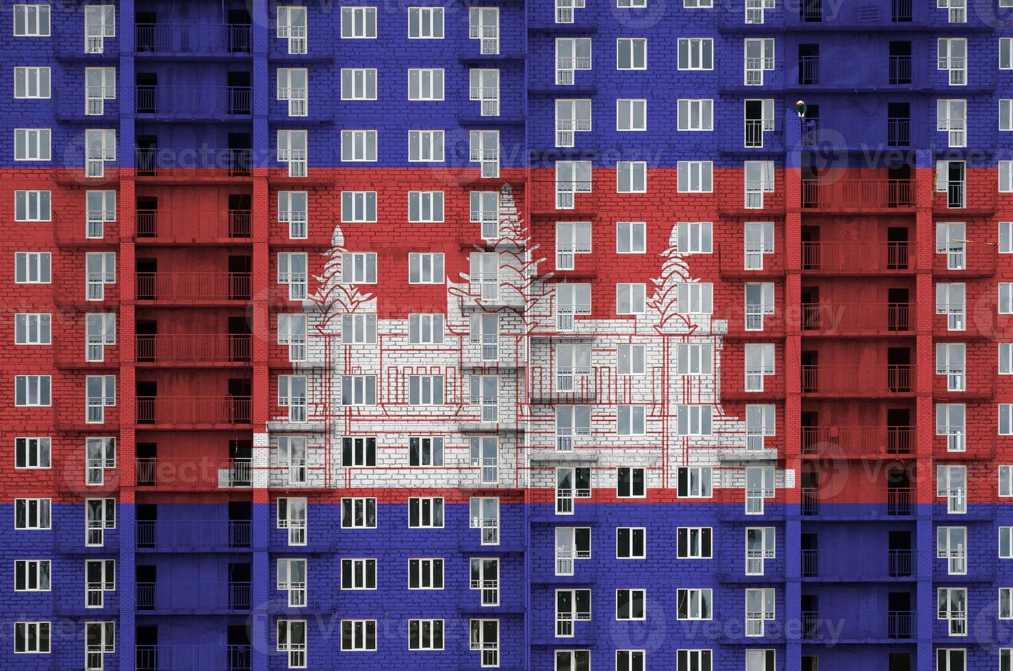 Cambodia flag depicted in paint colors on multi-storey residental building under construction. Textured banner on brick wall background photo