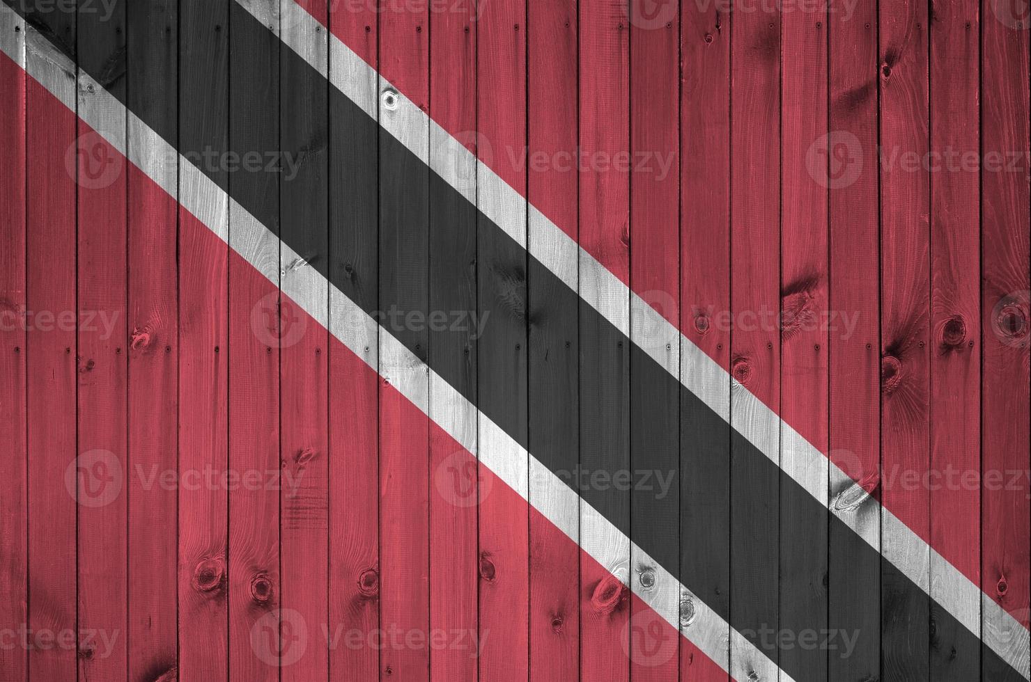 Trinidad and Tobago flag depicted in bright paint colors on old wooden wall. Textured banner on rough background photo