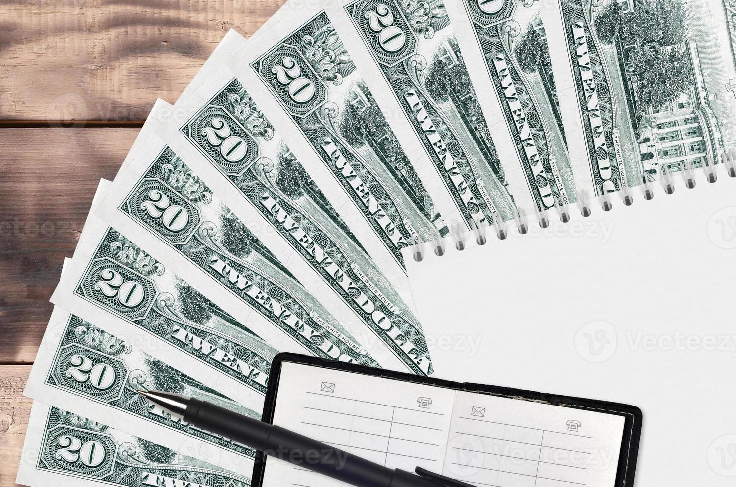 20 US dollars bills fan and notepad with contact book and black pen. Concept of financial planning and business strategy photo
