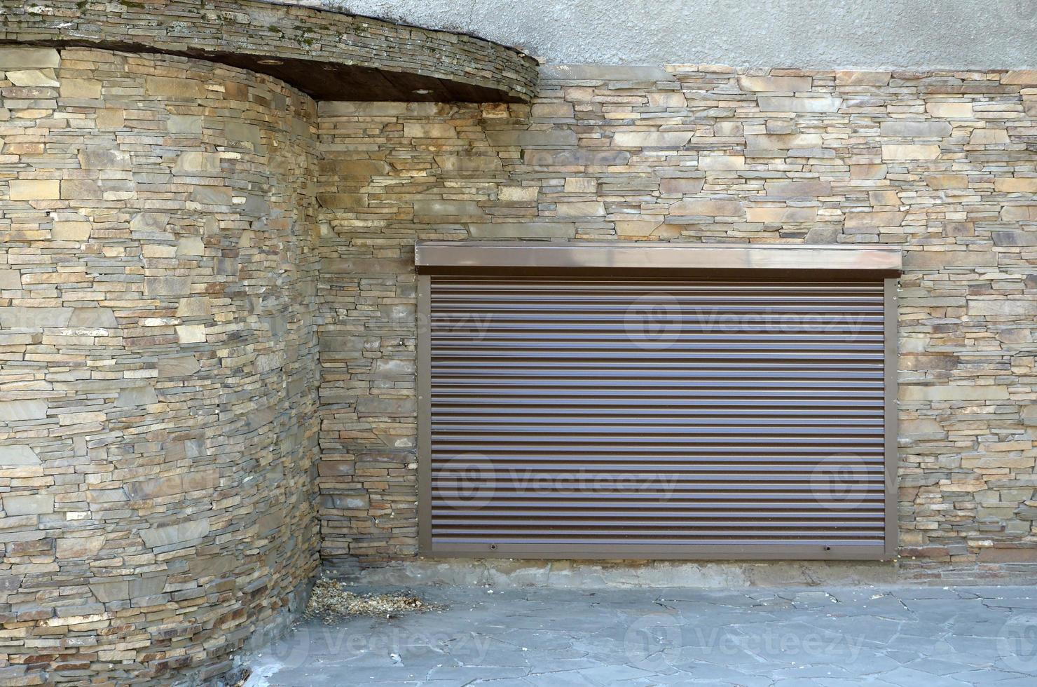 una ventana con persianas enrollables de metal marrón y decoración de paredes con piedra artificial foto