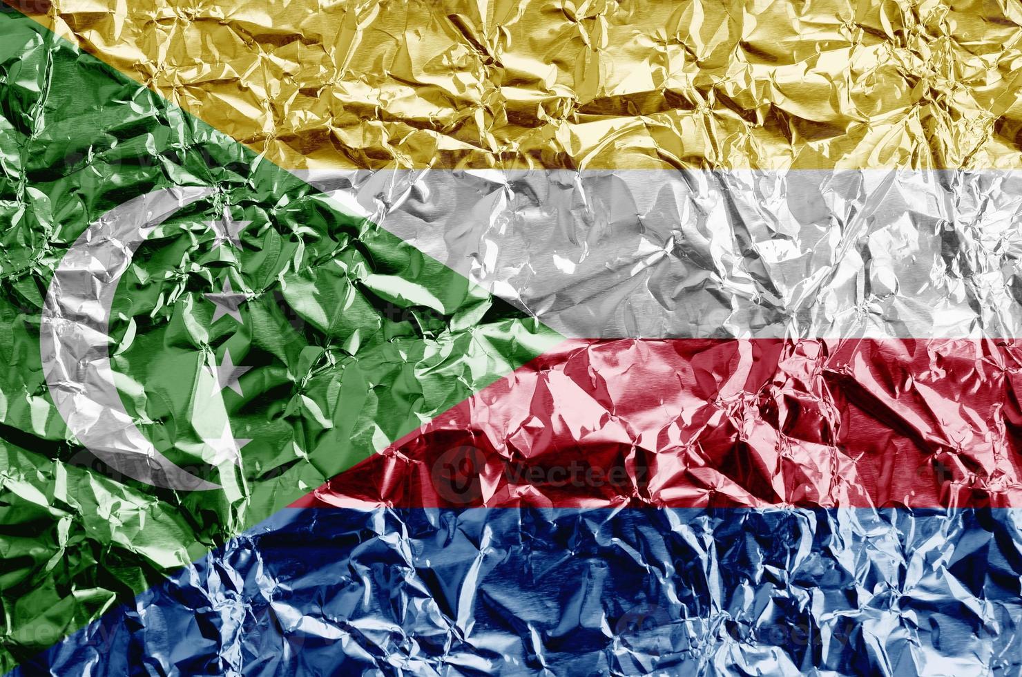 Comoros flag depicted in paint colors on shiny crumpled aluminium foil closeup. Textured banner on rough background photo