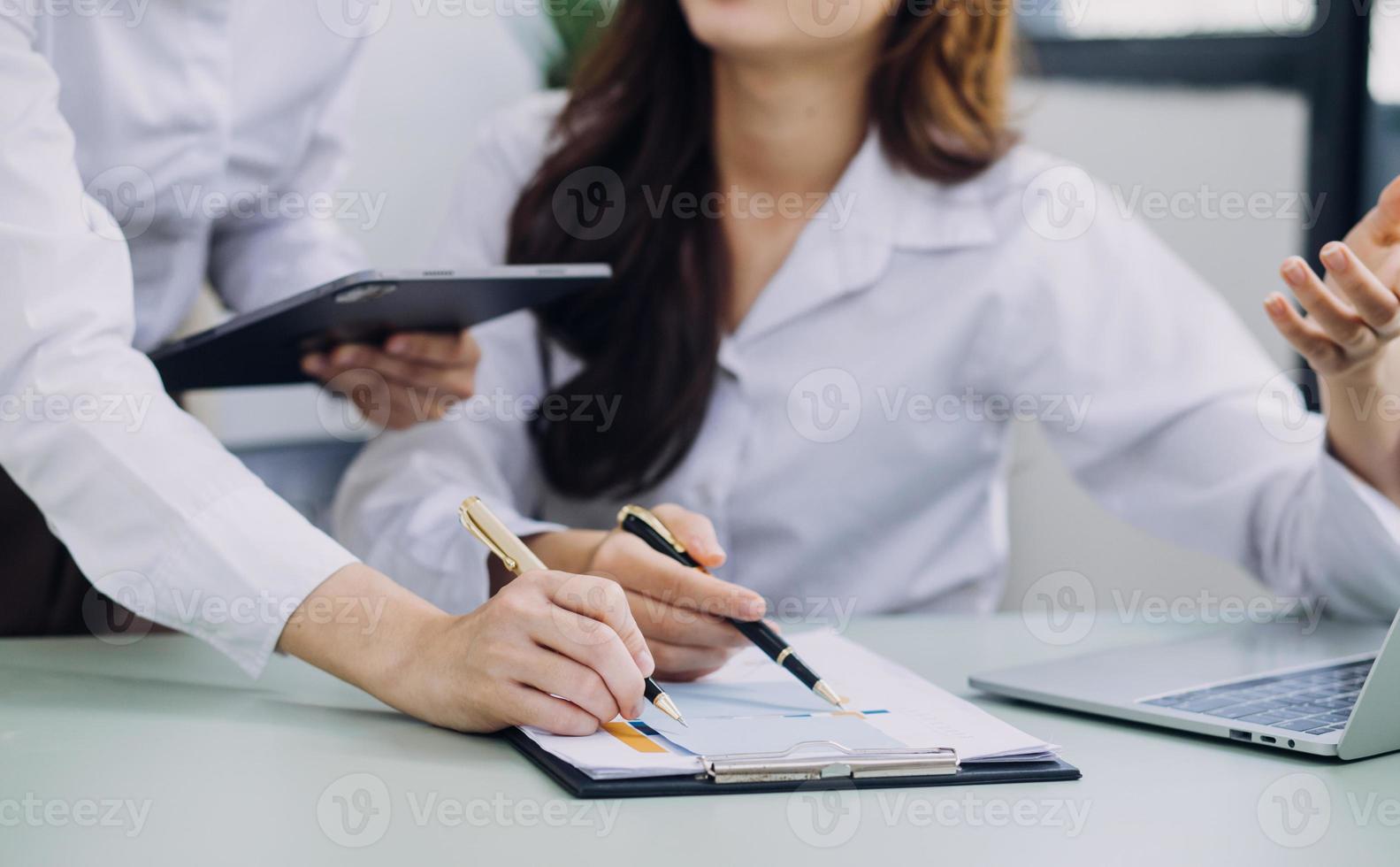 Young business woman sitting in office at table and using smartphone. On desk is laptop and tablet computer, on screen charts and graphs. Woman analyzing data. Student learning online. photo