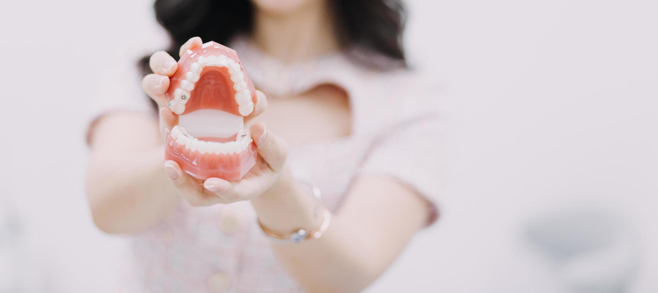 Stomatology concept, partial portrait of girl with strong white teeth looking at camera and smiling, fingers near face. Closeup of young woman at dentist's, studio, indoors photo