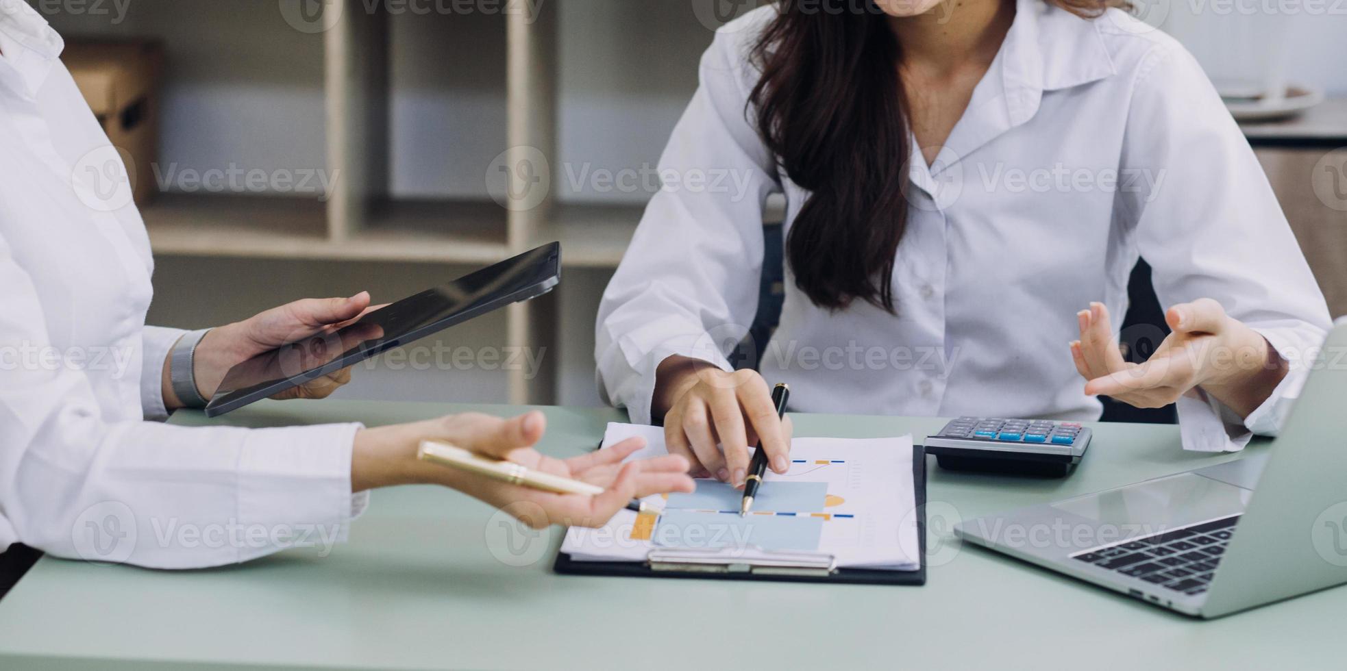 Young business woman sitting in office at table and using smartphone. On desk is laptop and tablet computer, on screen charts and graphs. Woman analyzing data. Student learning online. photo