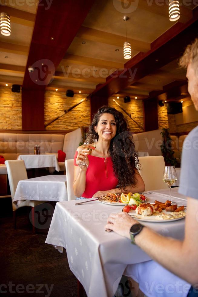 pareja joven almorzando con vino blanco en el restaurante foto