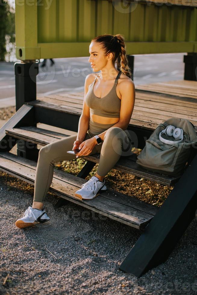 Young attractive female  runner taking break after jogging outdoors photo