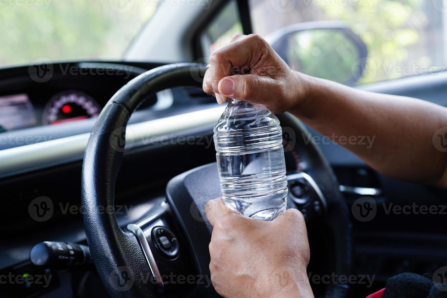 Asian woman driver hold cold water for drink in car, dangerous and risk
