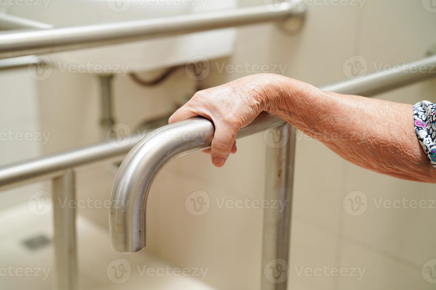 una anciana asiática usa un riel de soporte para el inodoro en el baño, barra de seguridad para pasamanos, seguridad en el hospital de enfermería. foto