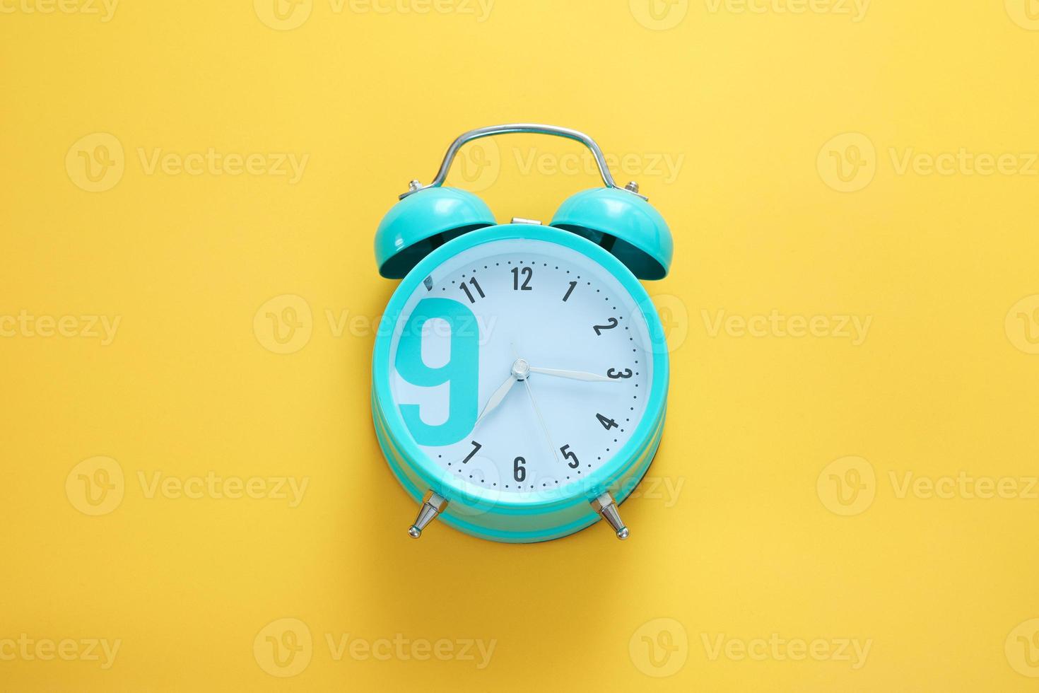 Blue alarm clock on the yellow background. Morning, time to wake up. Free space, copy space. photo