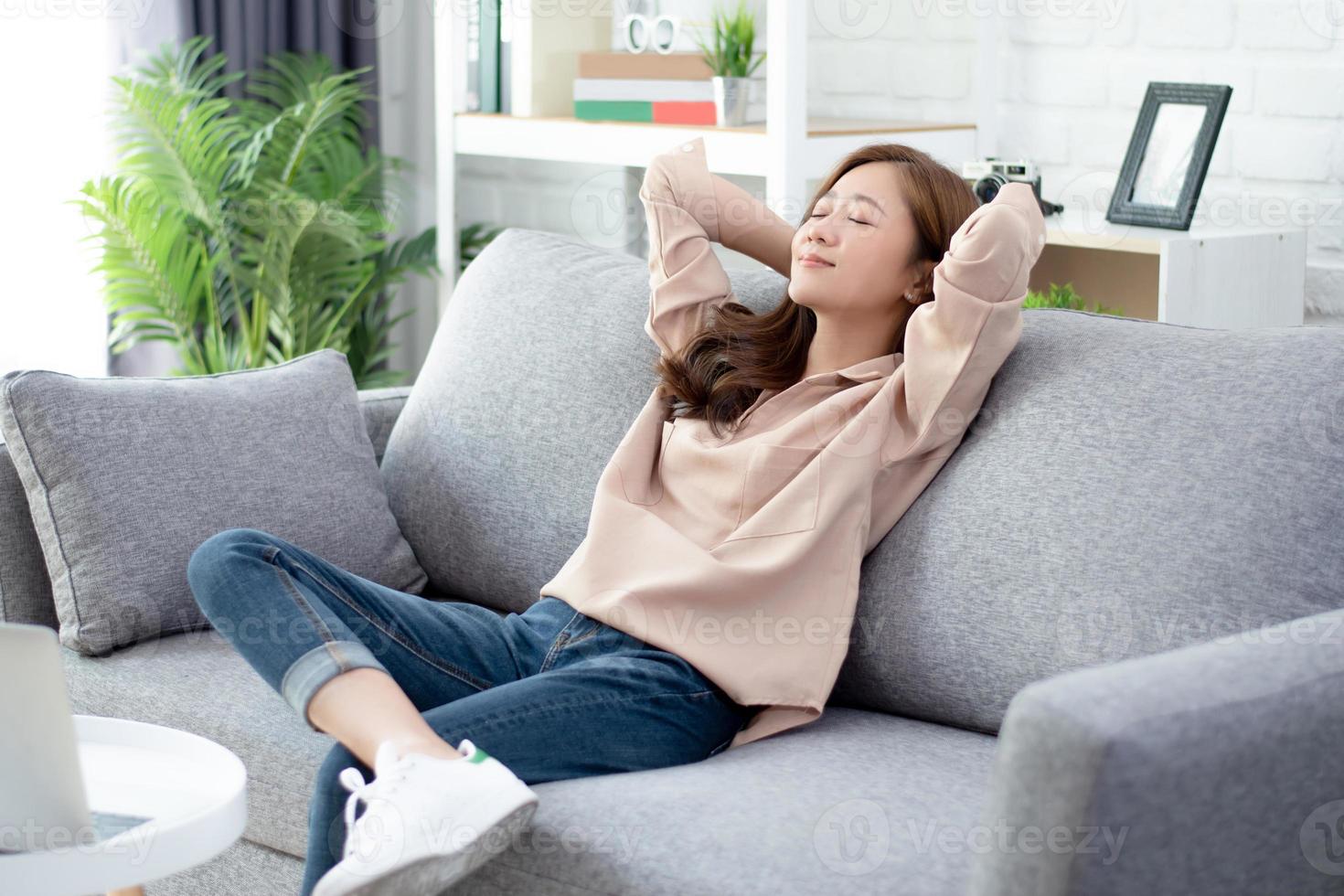 Beautiful Asian women feel relaxed on the weekends. She was sitting on a comfortable sofa at home. photo