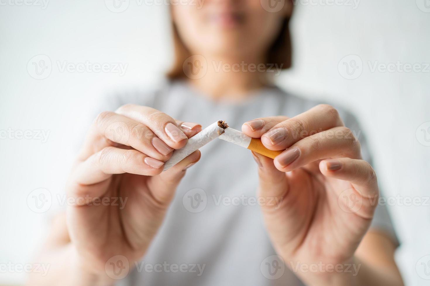 retrato de una hermosa niña sonriente sosteniendo un cigarrillo roto en la mano, feliz dejando de fumar. concepto de fumar, dejar el concepto de mal hábito, concepto de atención médica, no fumar. foto