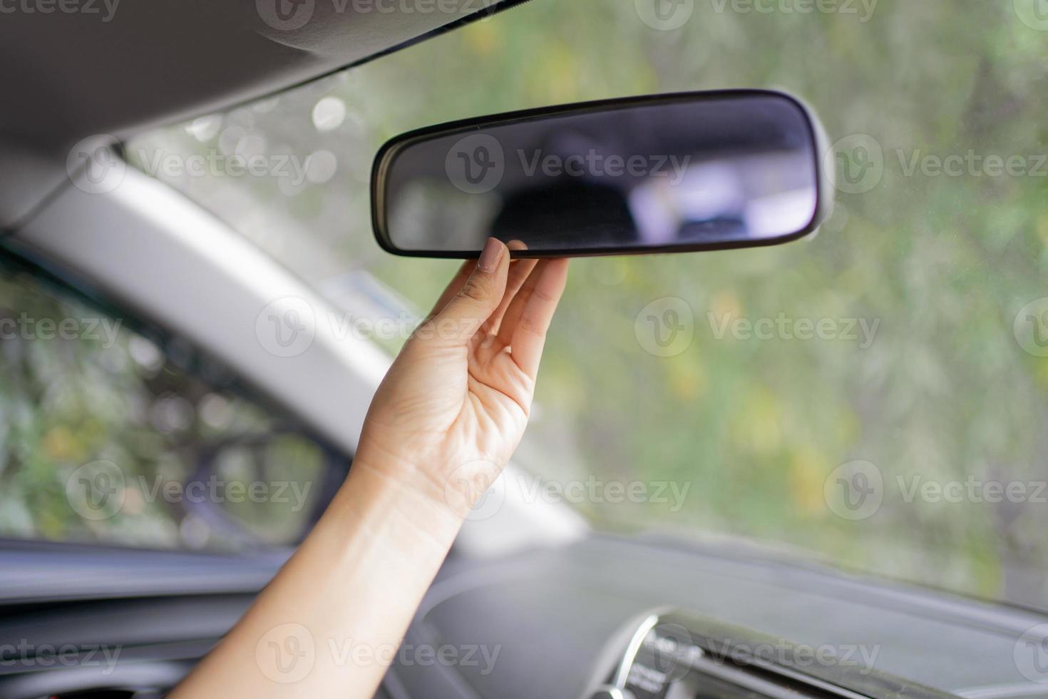 Asian women are adjusting the rearview mirror of the car photo