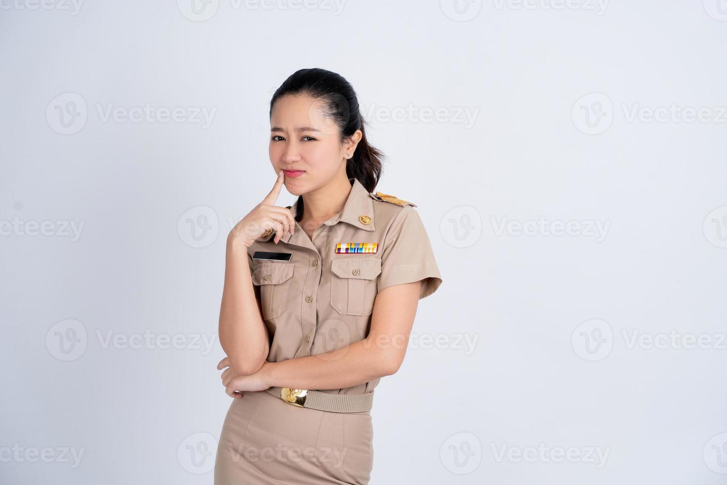 Portrait Asian beautiful young woman in brown work clothes. She smiling stand with your hands on your chin relaxed thinking about something about the question. photo