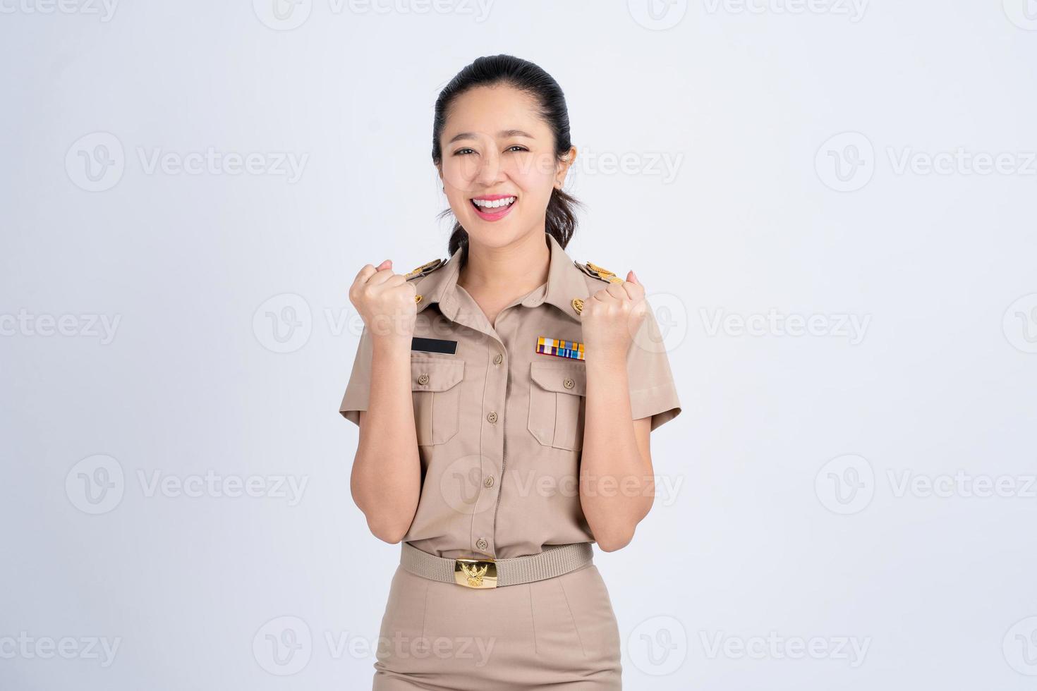 retrato de una alegre joven asiática vestida de trabajo. ella levantó su puño con una sonrisa feliz en su rostro como un gesto de celebración. foto