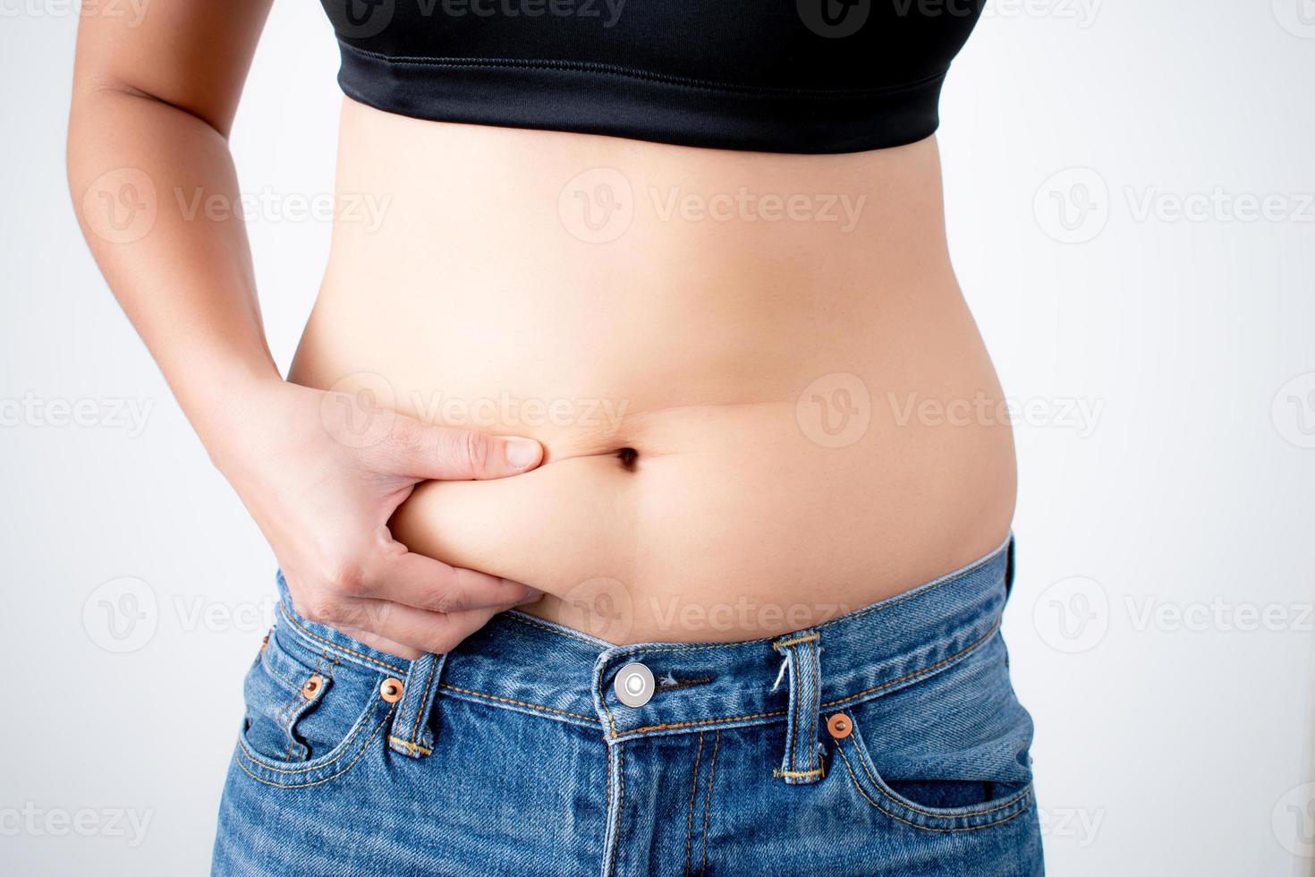 A close up of a woman's hand that grabs belly fat. With isolated background. photo
