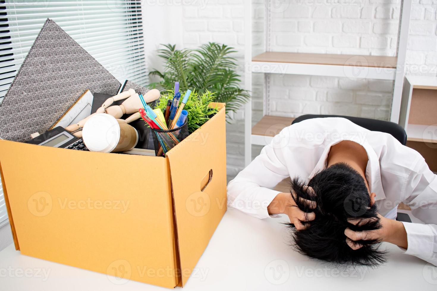 Young man bent his head on the white table. He stressed, because he was fired from his job. Unemployment Concept. photo