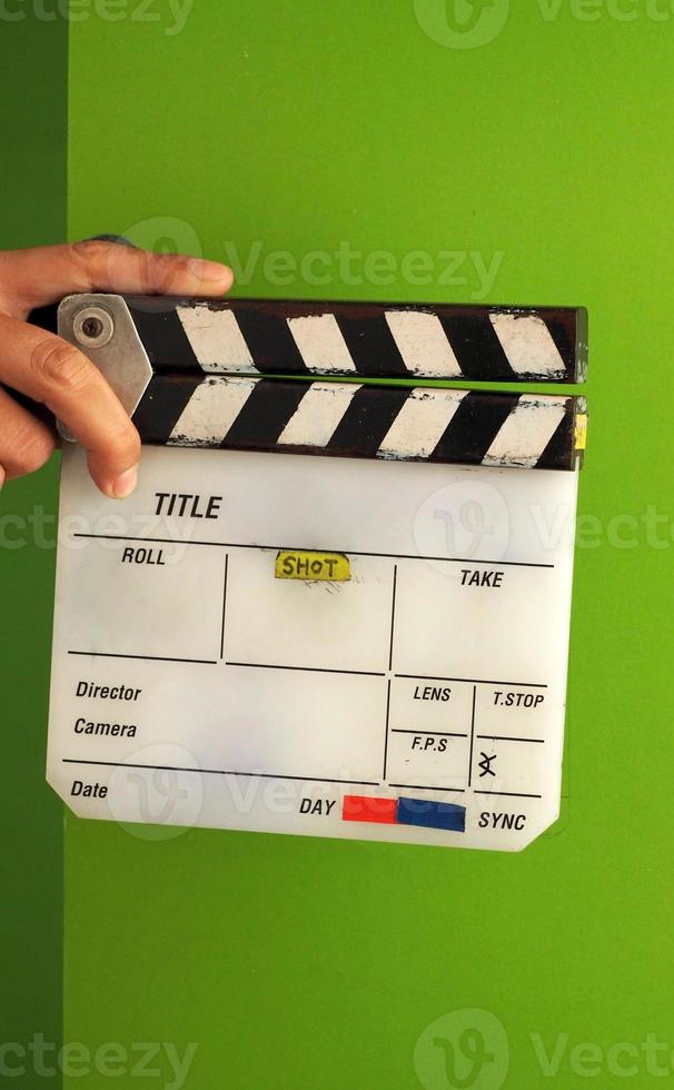 Movie slate board or clapper board and man hand and white color and green screen background in studio. photo
