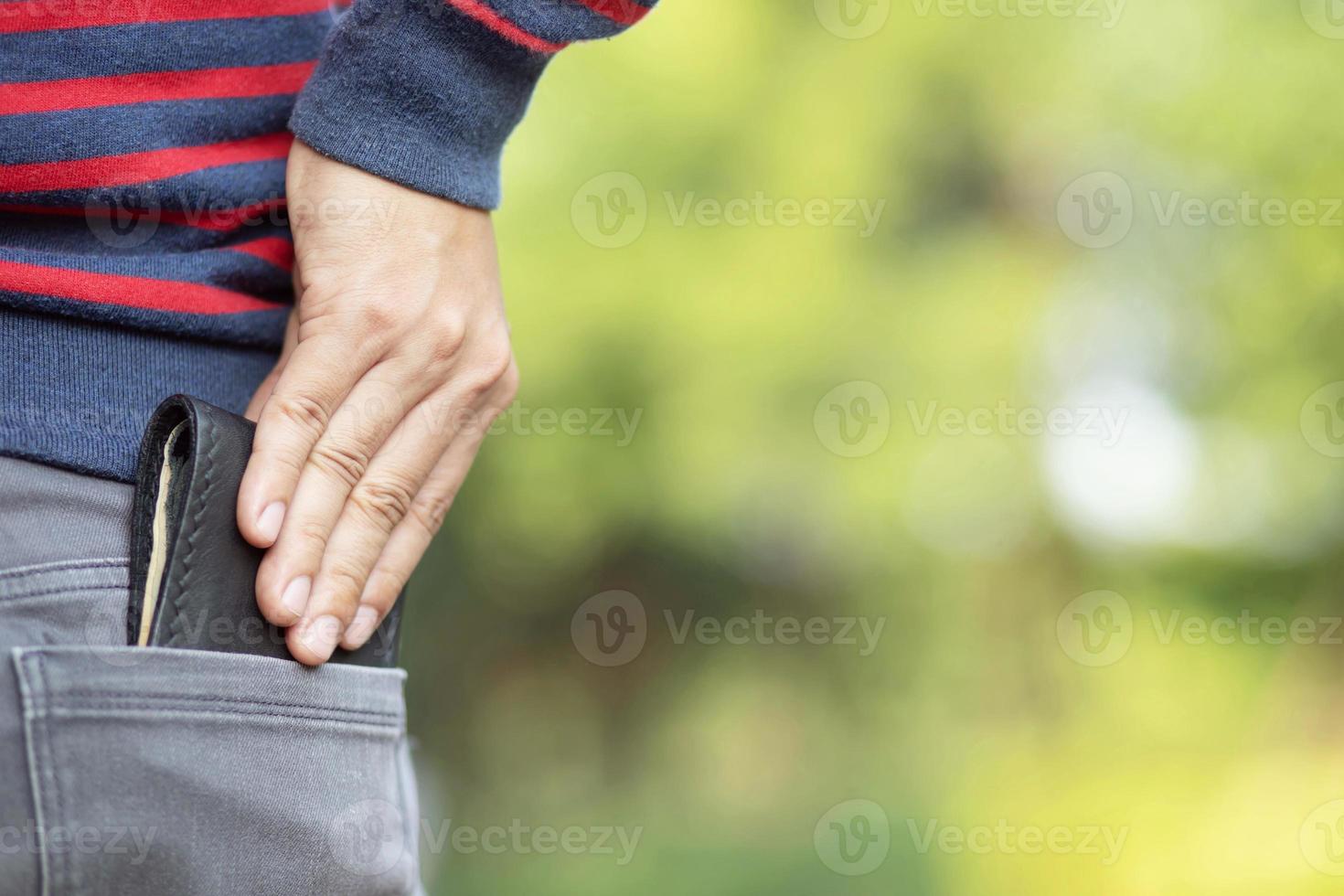 Confident young man posing in safe keeping your wallet in the back pocket of his back pocket pants. savings money finance. photo