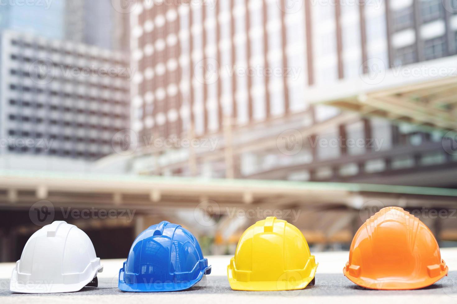 sombrero de casco de seguridad duro naranja, amarillo, azul, blanco en el proyecto en el edificio del sitio de construcción en el piso de concreto en la ciudad. casco para obrero como ingeniero o trabajador. concepto de seguridad primero. foto