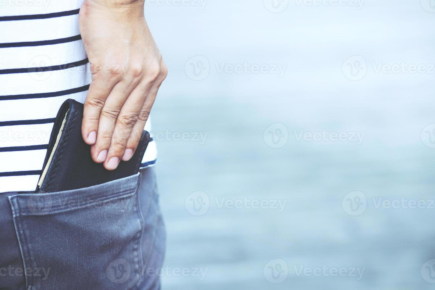 hombre de negocios confiado posando en una caja fuerte manteniendo su billetera en el bolsillo trasero de sus pantalones de bolsillo trasero. dinero de ahorro. foto