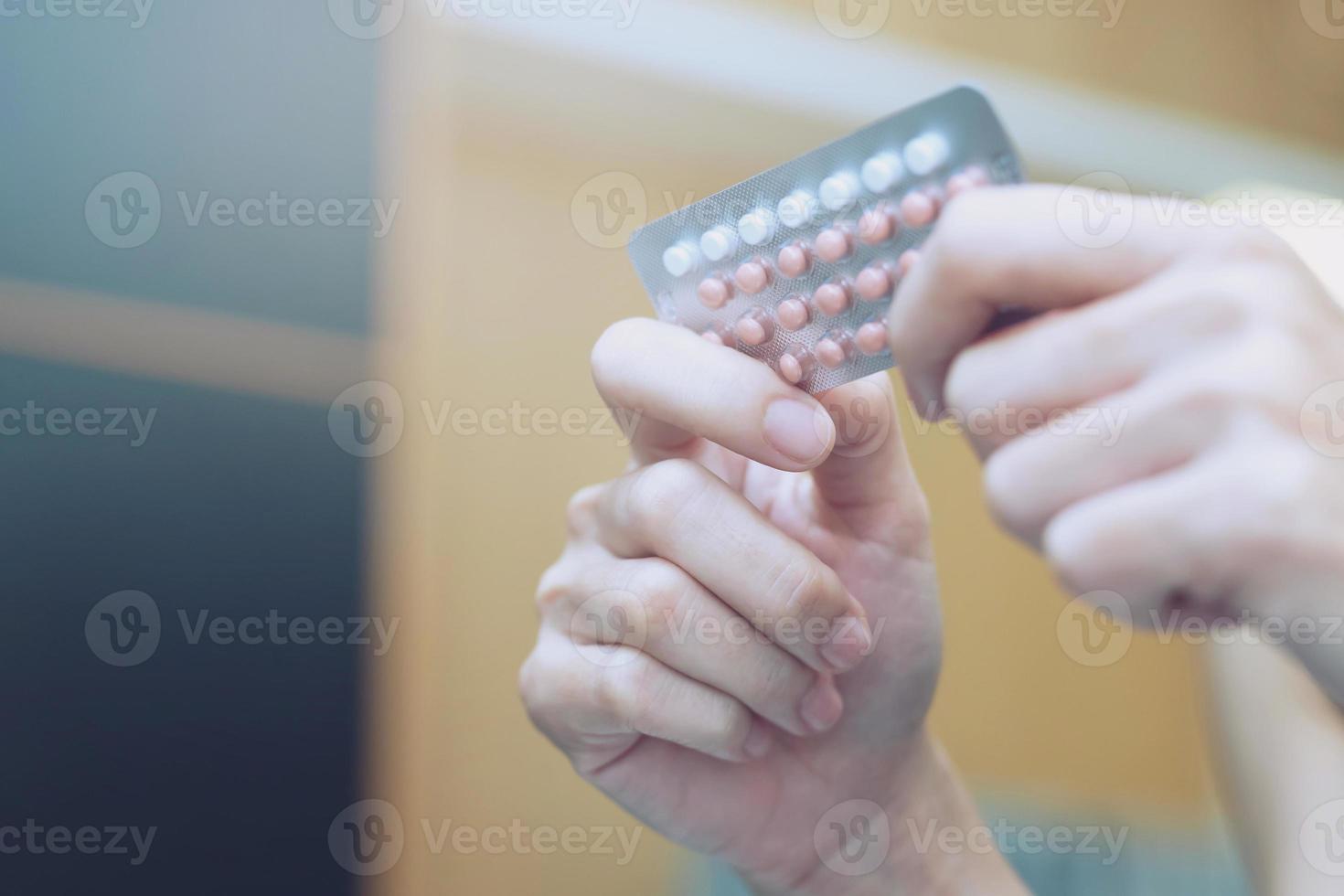 manos de mujer abriendo píldoras anticonceptivas en la mano. comiendo píldora anticonceptiva. foto