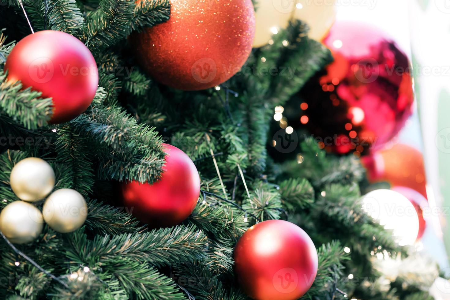Closeup of red bauble hanging from a decorated christmas tree on blurred of  lights with decorated tree, sparkling and bokeh background. copy space for your text. photo