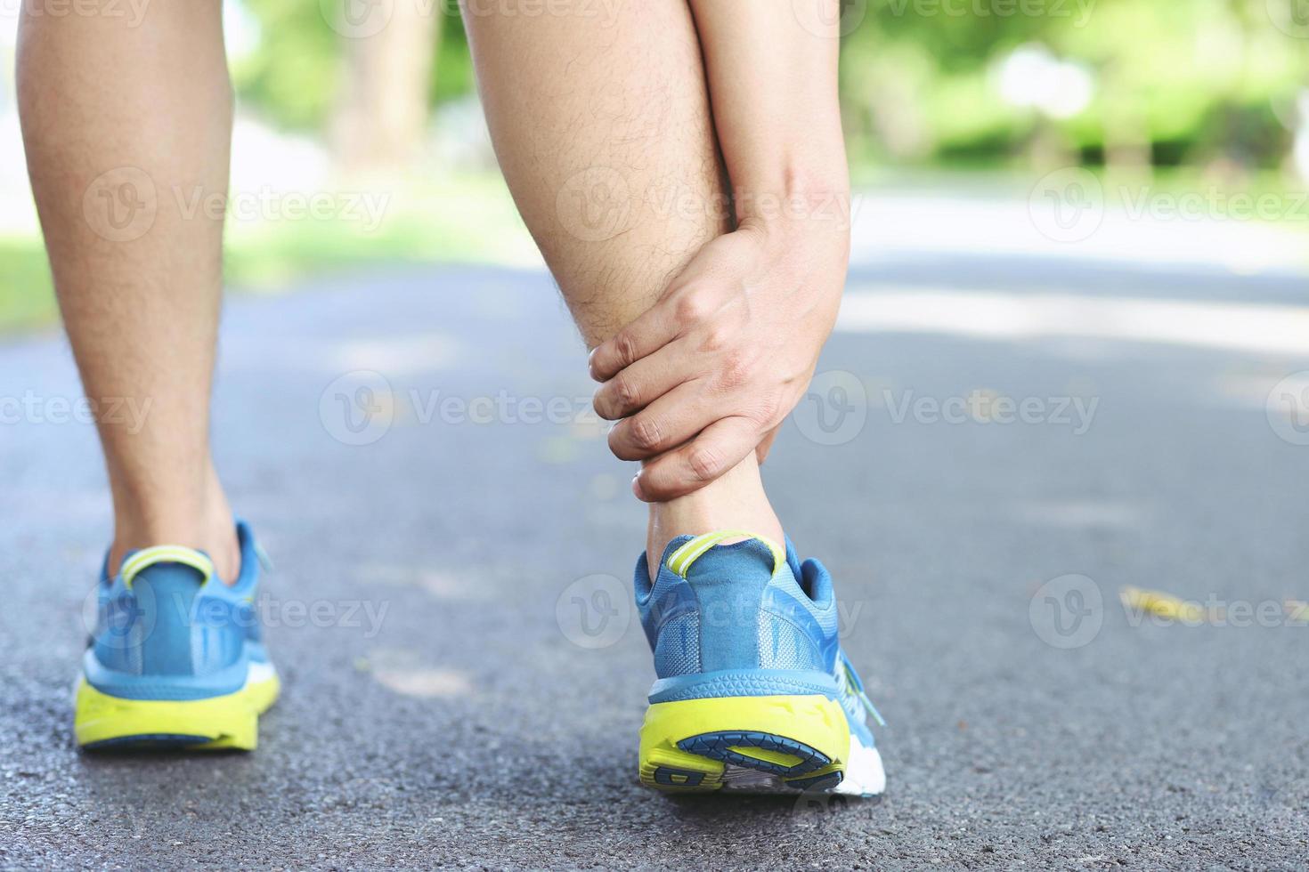 Runner touching painful twisted or broken ankle. Athlete runner training accident. Sport running ankle sprained sprain cause injury knee. and pain with leg bones while run in outdoor the park. photo