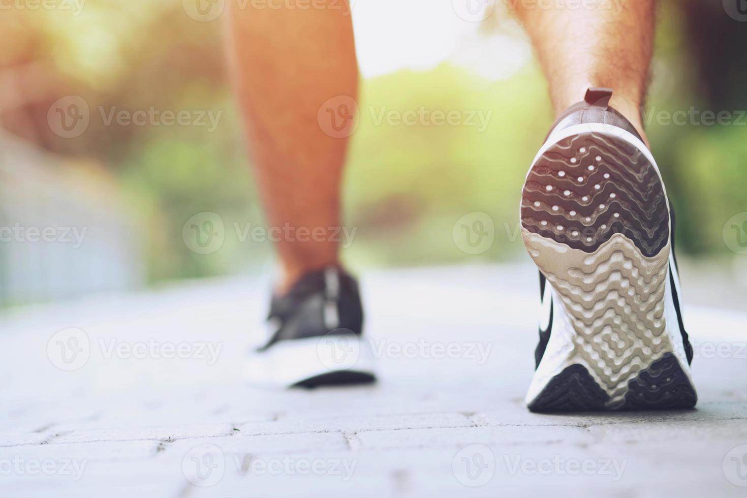 Sportsman foot runner trail running outdoors. close up on shoe behind of a man running fitness jogging workout uphill in autumn trail of nature and stones. exercise healthy lifestyle and sport concept photo