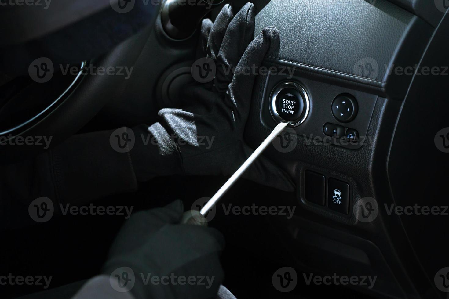 cierre la mano del ladrón de coches sujetando el destornillador y el guante negro robando el automóvil tratando de manejar la puerta para ver si el vehículo está desbloqueado tratando de entrar en el interior. foto
