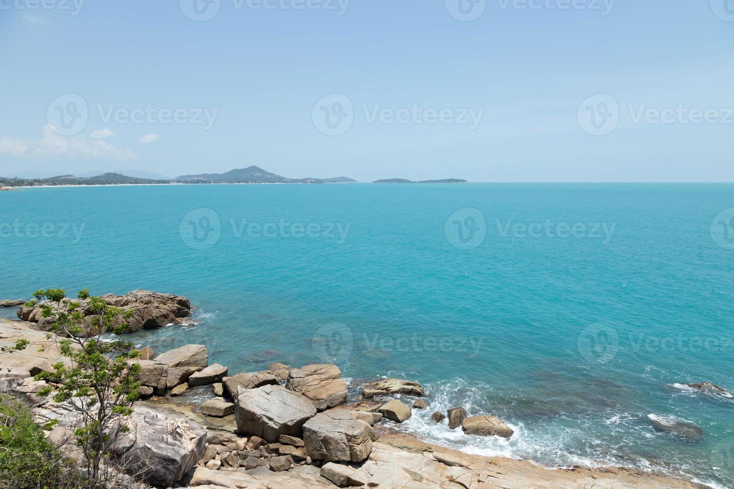 vista de la costa de las olas del mar y la fantástica costa de la playa rocosa en la isla y el cielo de fondo con montaña, naturaleza salvaje. costa del paisaje tropical. Hora de verano. concepto de vacaciones de viaje. foto