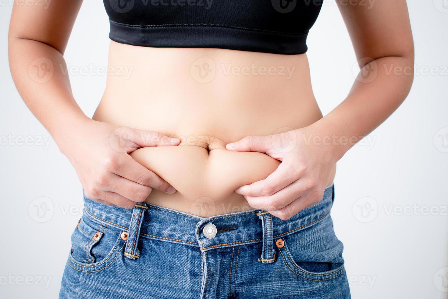 Woman holding excess fat on her belly on a white background photo