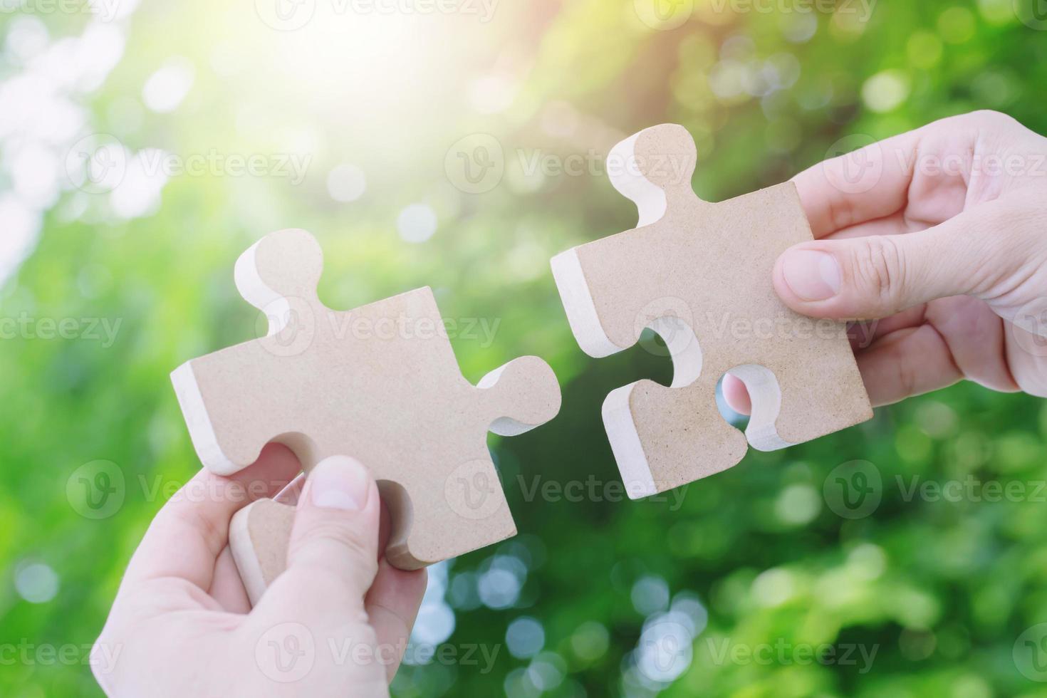 two hands person trying to connect couple Jigsaw paper white puzzle piece with tree fresh background. one part of whole. symbol of association and connection. success and business solution strategy. photo