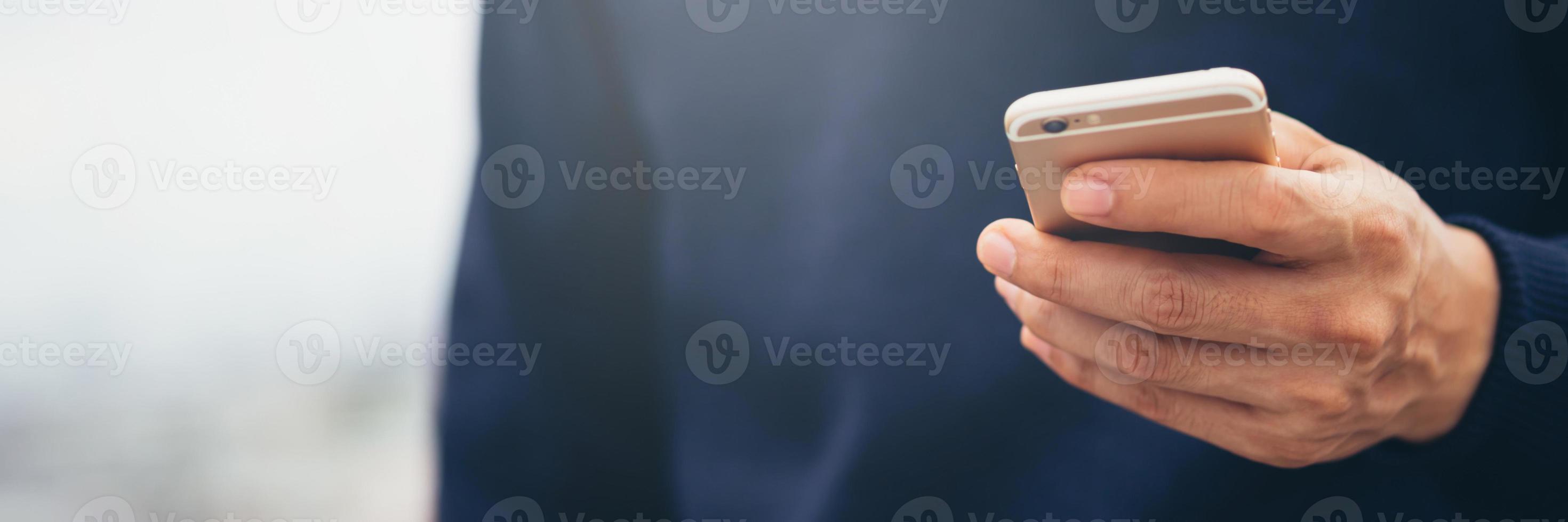 joven usa camisa a cuadros. cierre la mano usando el teléfono celular durante el descanso en el sofá. sentado viendo un mensaje en un teléfono inteligente móvil durante el descanso, relájese. enfoque suave. foto