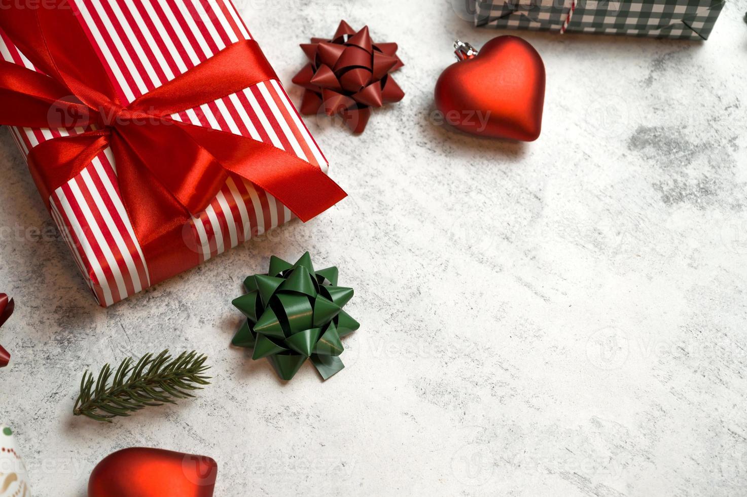 Top view on gift box in red paper with bows and ornaments near on concrete background. Flat lay with place for text photo