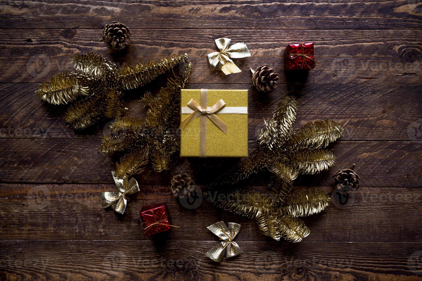 el piso de navidad vintage yacía en colores dorados y rojos. caja de regalo brillante rodeada de elementos de decoración y ramas de abeto pintadas en oro foto