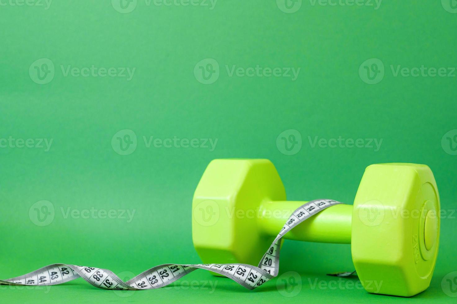Workouts and fitness concept. Healthy lifestyle. Green dumbbells and measuring tape photo