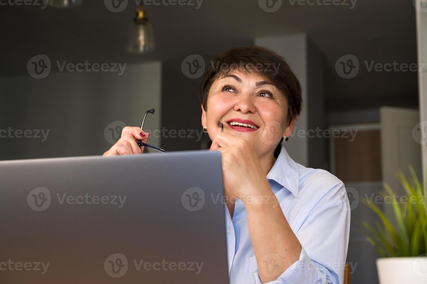 distracted dreamy senior woman sitting at the table with laptop.modern technologies possibilities concept photo