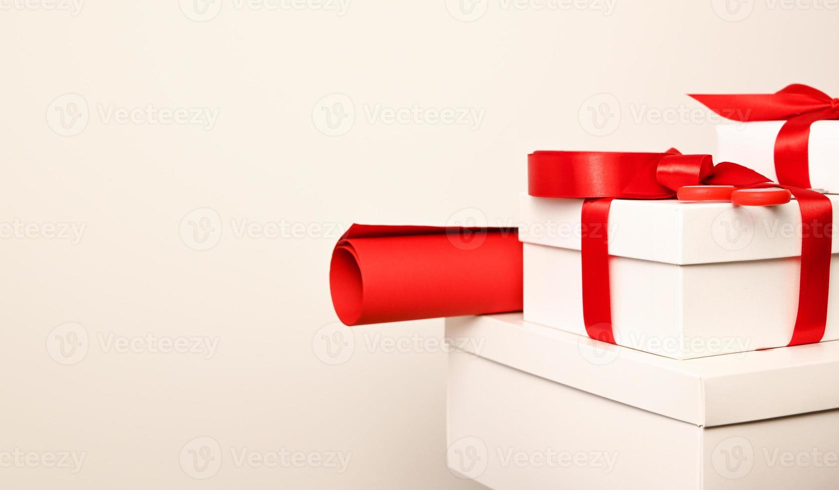 pila de regalos blancos con lazos rojos y papel de regalo rojo sobre fondo blanco. copyspace.navidad foto