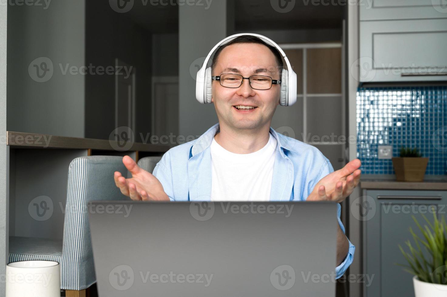 Happy asian man with headphones on having online video call at work or talking with customer.Or teacher giving lecture online.Work from home concept.Online education photo