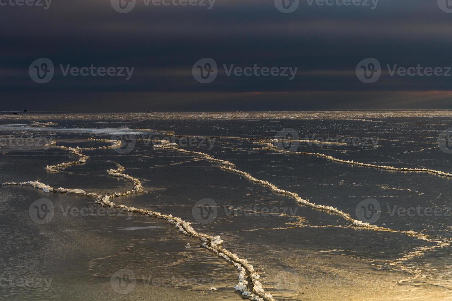 costa del mar báltico con guijarros y hielo al atardecer foto