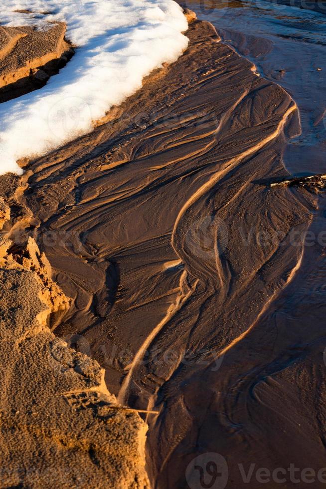 costa del mar báltico con guijarros y hielo al atardecer foto