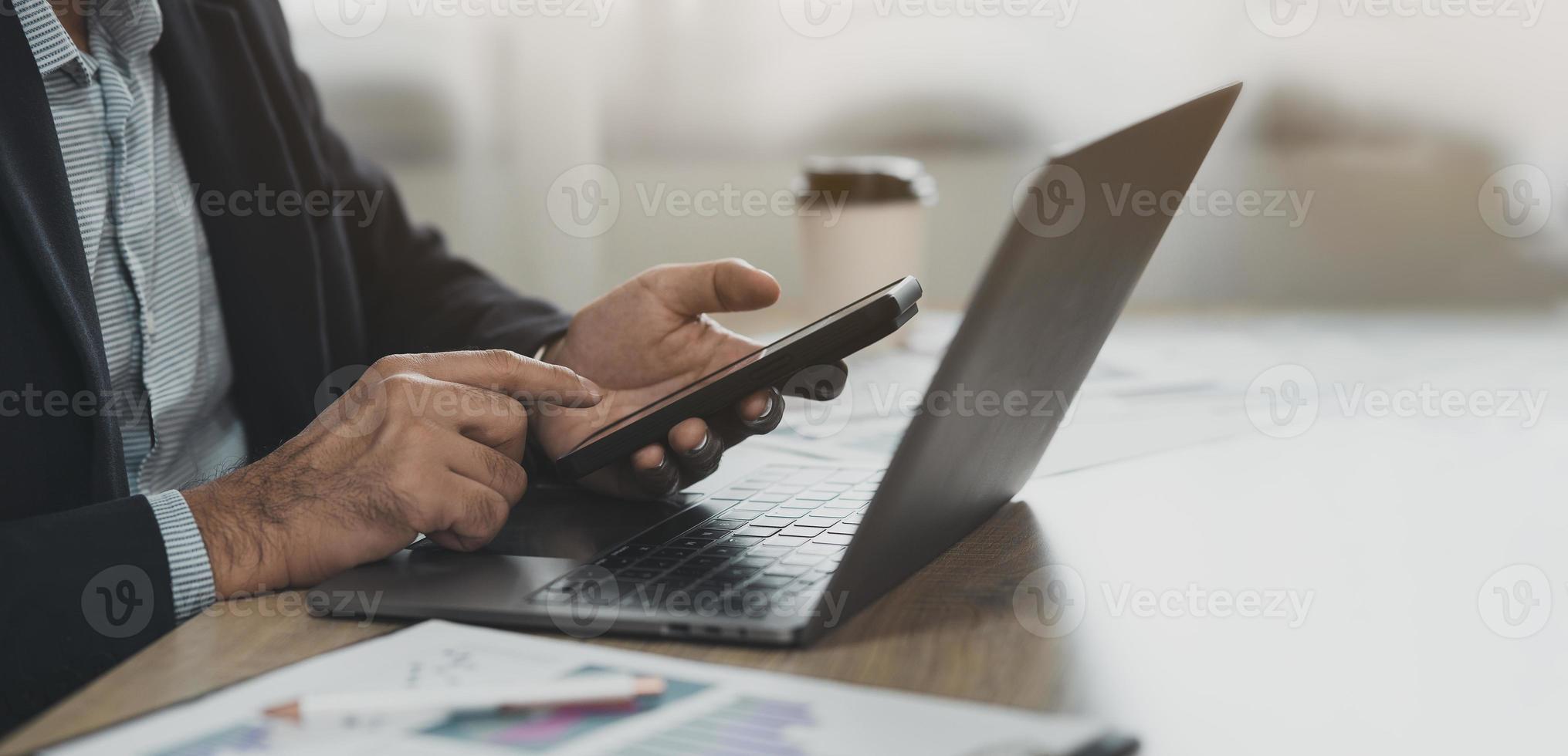 Crop picture. business man using smartphone working with laptop on table, mobile phone to search or social media or shopping online or stock or crypto currency. Smart phone conversation conferrence. photo