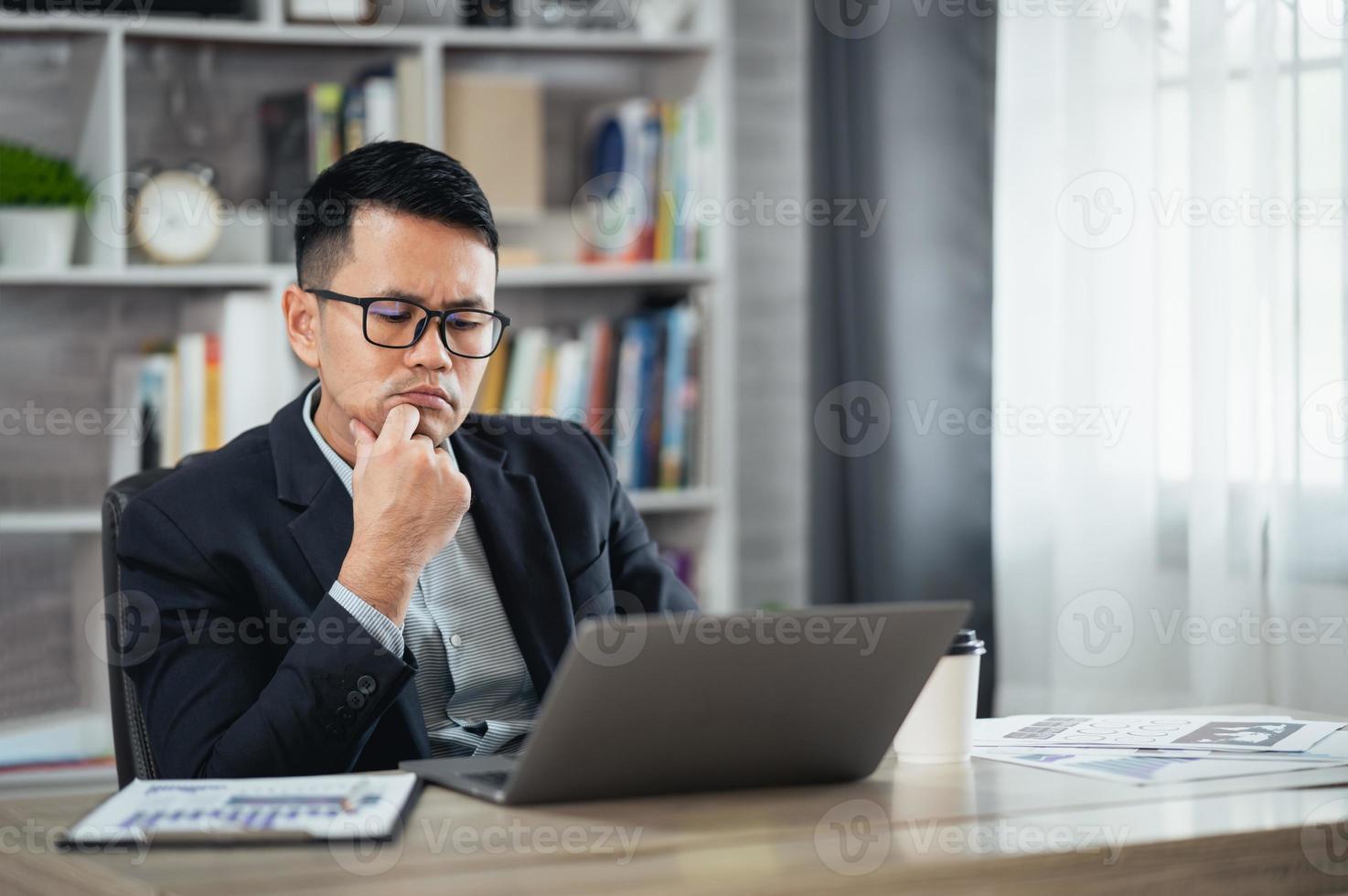 Asian business freelance man wear glasses and suit having stressful depression sad time while working on laptop at home. Depression man sad serios working from home. Working at anywhere concept. photo